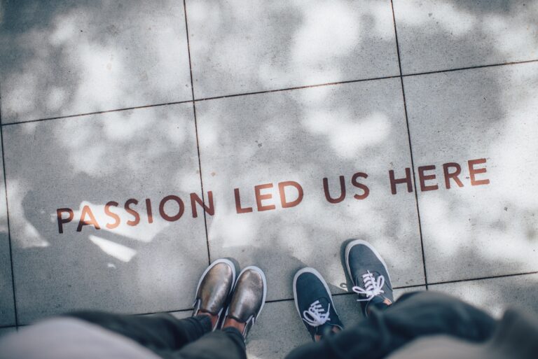 Two pairs of feet standing on a sidewalk, with the phrase 'Passion led us here' painted below.